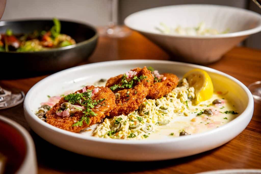 Drift crab cakes in a white dish on a wood table top