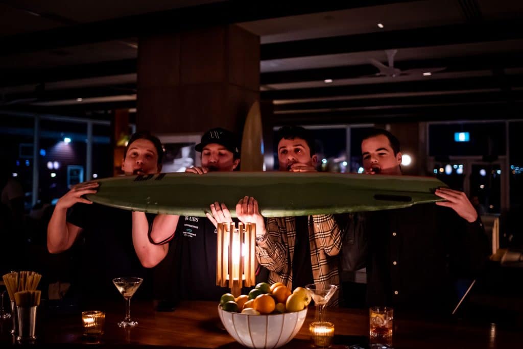 Guests taking shots off a surfboard at Salt + Ash
